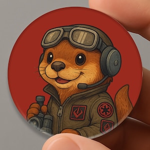 May include: A round, red button featuring a cartoon otter wearing a pilot's uniform, headset, and goggles. The otter is holding a small device and smiling. The design has a Star Wars theme.