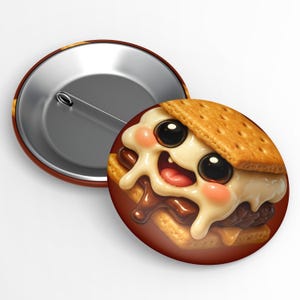 May include: A round button with a cartoon s'more design. The s'more has a smiling face with large black eyes, pink cheeks, and a red tongue. The button's background is brown, and the back is silver with a pin.