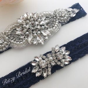 The silver wedding garter features a band with sparkling rhinestone accents, creating a captivating focal point. The rhinestones are strategically placed along the garter, catching the light and adding a subtle shimmer.