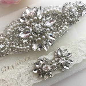 The garter set includes a smaller coordinating garter designed for the traditional garter toss at the wedding reception. It mirrors the design of the main garter, with its ivory lace band and sparkling rhinestone accents.