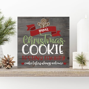 May include: A rustic wooden sign with a gingerbread man graphic and the text "Nana's Christmas Cookie Testing Facility - cookie testers always welcome". The sign is painted in red, green, and white.