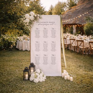 Pu&ograve; includere: Un alto cartello rettangolare per il tableau de mariage con il testo "OUR FAVORITE PEOPLE" e "please find your seat" sopra nove liste di tavoli. &Egrave; decorato con composizioni floreali bianche, due lanterne nere e candele cilindriche.