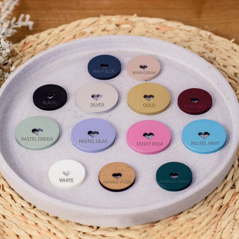 May include: Assortment of 14 round wooden buttons with a heart design in various colors, including black, silver, gold, burgundy, pastel green, pastel lilac, dusty rose, pastel mint, white, natural wood, emerald green, navy blue, and boho cream.