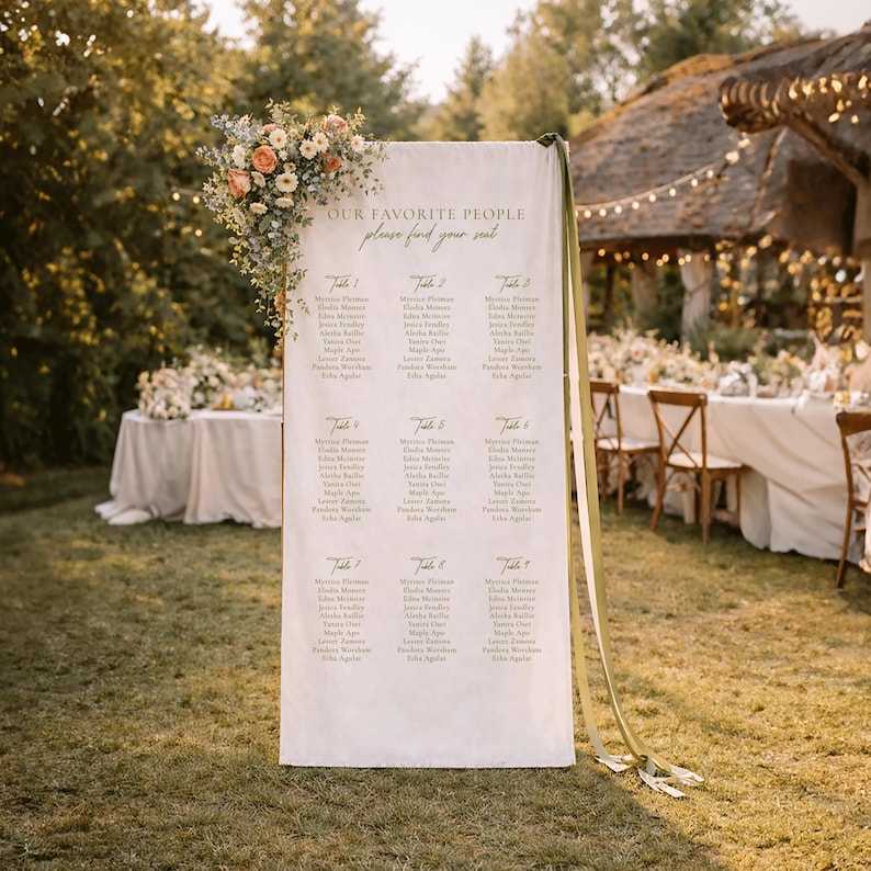 Pu&ograve; includere: Un alto cartello rettangolare in tessuto bianco per il tableau de mariage con il testo "OUR FAVORITE PEOPLE please find your seat" e nove tavoli. Il cartello &egrave; decorato con una composizione floreale di fiori color pesca e bianchi.