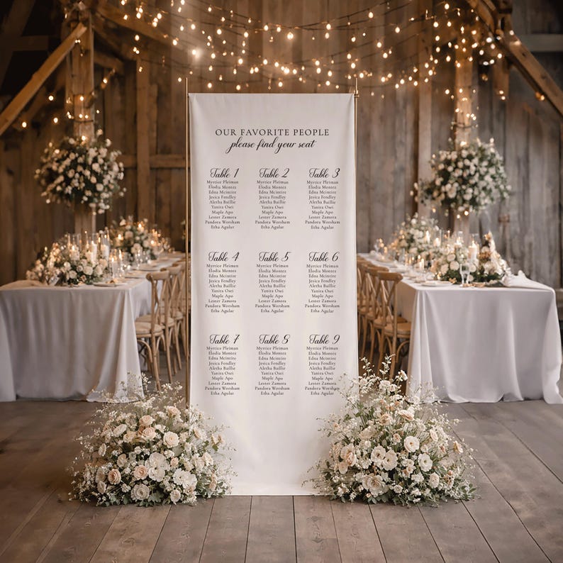 Pu&ograve; includere: Un alto cartello verticale bianco per il tableau de mariage su un supporto in metallo dorato. Il cartello presenta il testo "OUR FAVORITE PEOPLE" e "please find your seat" sopra un elenco di nove tavoli con nomi in caratteri neri.
