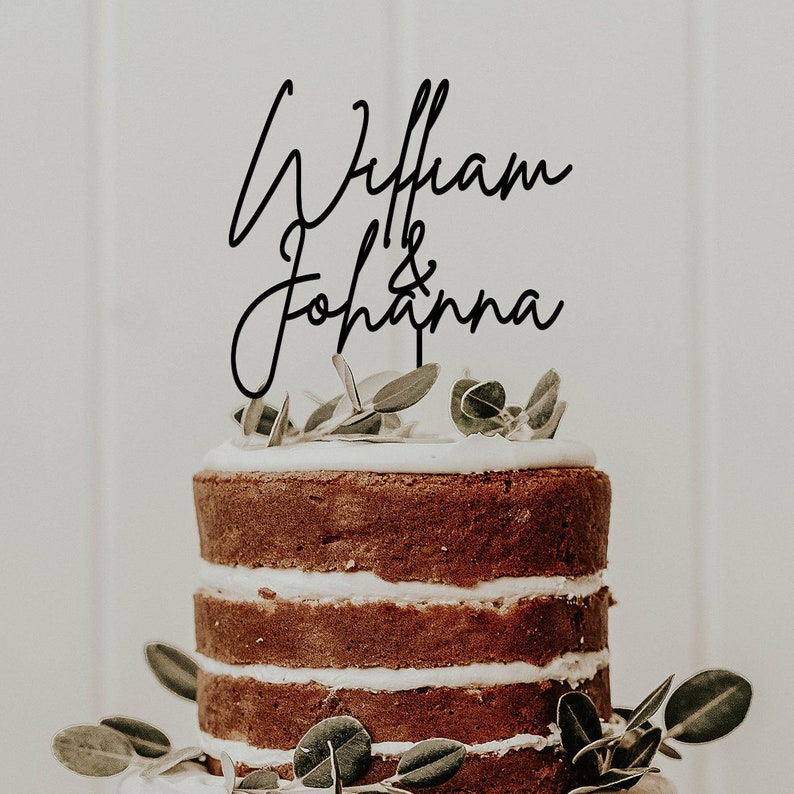 May include: A wedding cake topper with the names "William & Johanna" written in a cursive script.