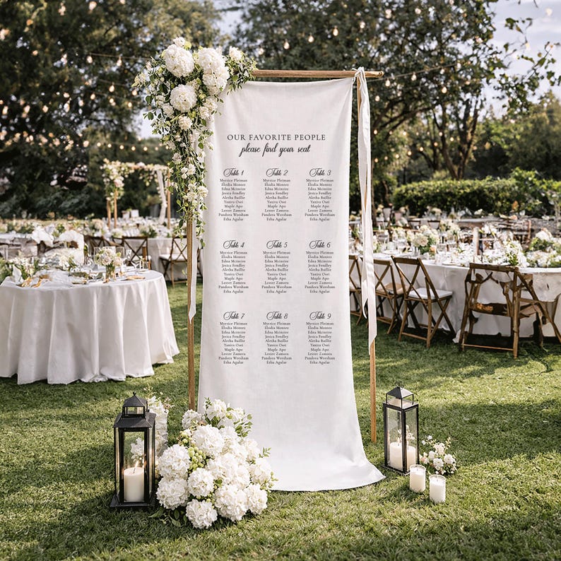 Pu&ograve; includere: Un alto cartello in tessuto bianco per il tableau de mariage sospeso a una cornice in legno, con il testo OUR FAVORITE PEOPLE please find your seat e nove liste di tavoli. &Egrave; decorato con ortensie bianche e due lanterne nere.