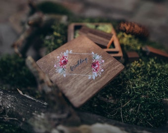 May include: A wooden box with a floral design and the word "wedding" printed on it. The box is sitting on a bed of moss.