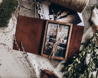 Könnte beinhalten: Ein braunes Lederfotoalbum mit einem Holzrahmen, der ein Foto von einem Gebäude mit einem Fenster und einem daran befestigten Band zeigt.