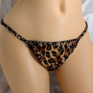 May include: Leopard print satin lingerie with black trim. The lingerie is a low-rise style with a cheeky cut.