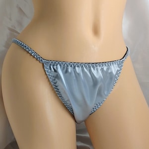 May include: Light blue satin lingerie with black trim. The lingerie has a low rise and a cheeky cut.