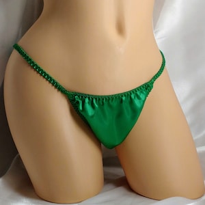 Peut inclure: Lingerie en satin vert avec une coupe taille basse et des bretelles fines.