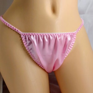 May include: Pink satin lingerie with a white trim. The lingerie is made of a soft, silky fabric and has a low-cut design.