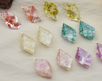 May include: Assortment of 10 diamond-shaped resin charms with pressed flowers. The charms are in various colors, including green, pink, white, and yellow. Each charm has a gold loop for attaching to jewelry.