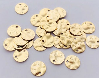May include: A collection of gold-colored metal discs with a hammered texture. The discs have two holes punched through them.