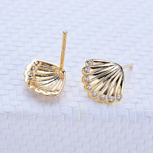 May include: A pair of gold-tone earrings shaped like seashells with clear rhinestones.