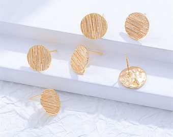 May include: Five gold-toned round earring blanks with a textured surface. The earring blanks have a post on the back for attaching to an earring.