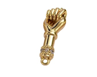 May include: Gold charm in the shape of a fist with a band of clear rhinestones around the wrist.