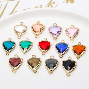Puede incluir: Surtido de doce abalorios de forma triangular de color dorado con un centro de cristal transparente. Cada abalorio tiene dos lazos en la parte superior para sujetarlo a joyas u otras manualidades.