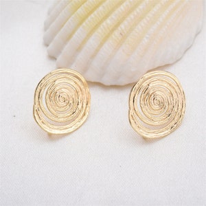 May include: A pair of gold-toned spiral earrings. The earrings are round and have a textured, swirling design.