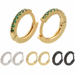 May include: Set of six hoop earrings in three different colors: gold, silver, and black. Each earring features a row of small, sparkling stones.