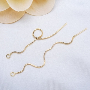 Può includere: Un paio di delicati orecchini a filo color oro. Ogni orecchino presenta una sottile catena a maglie quadrate che pende da un piccolo anello nella parte inferiore e un perno dritto nella parte superiore. Gli orecchini sono esposti su una superficie bianca.