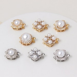 May include: Eight pearl and crystal clasps for jewellery making. Four clasps are gold-toned and four are silver-toned. Each clasp features a square design with a large pearl in the centre and smaller pearls around the edges.