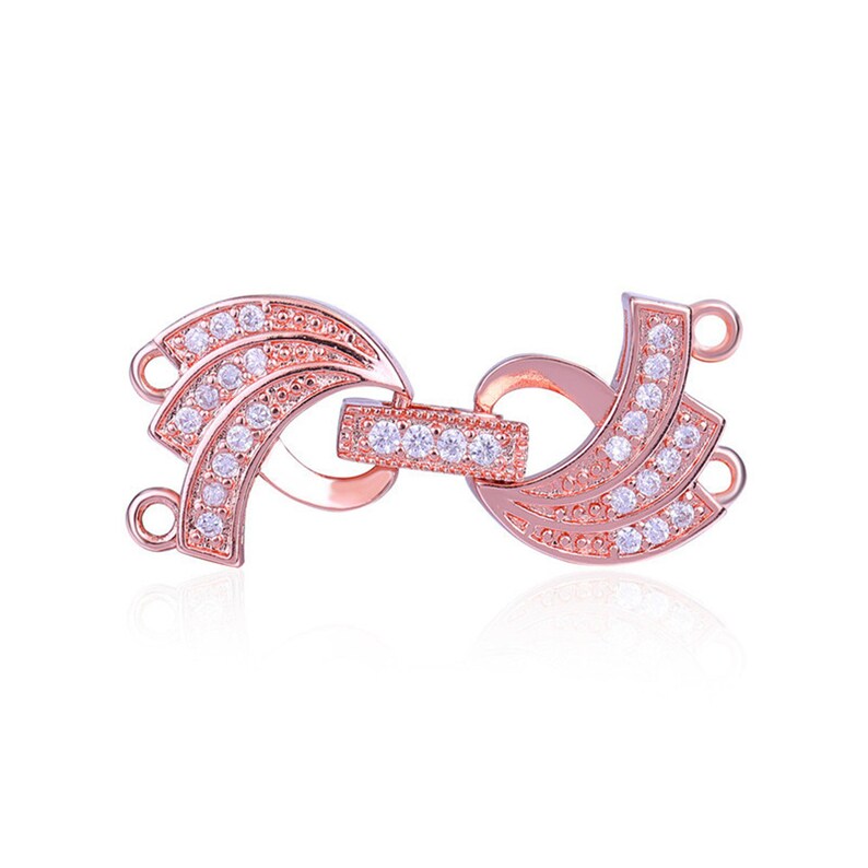 May include: Rose gold tone metal clasp with clear cubic zirconia stones. The clasp has two loops on one side and a single loop on the other side.