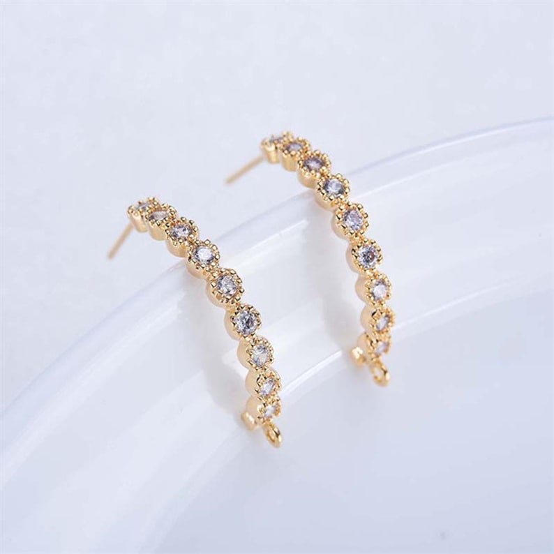 May include: A pair of gold hoop earrings with a row of clear cubic zirconia stones.