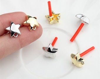 May include: Five gold and silver star-shaped charms with red and white accents. The charms are on a white surface.