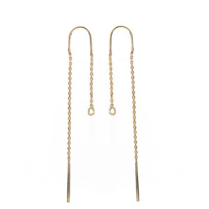May include: A pair of gold-toned earring findings with a chain and a small loop at the top. The chain is about 2 inches long and has a small, straight piece at the bottom.