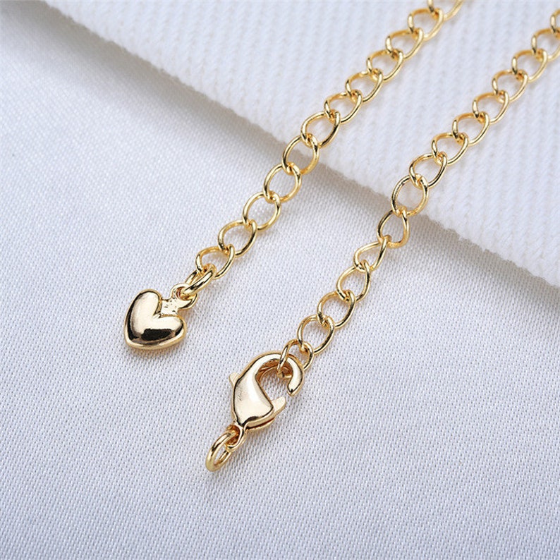 May include: A gold chain necklace with a heart-shaped clasp and a lobster claw clasp.