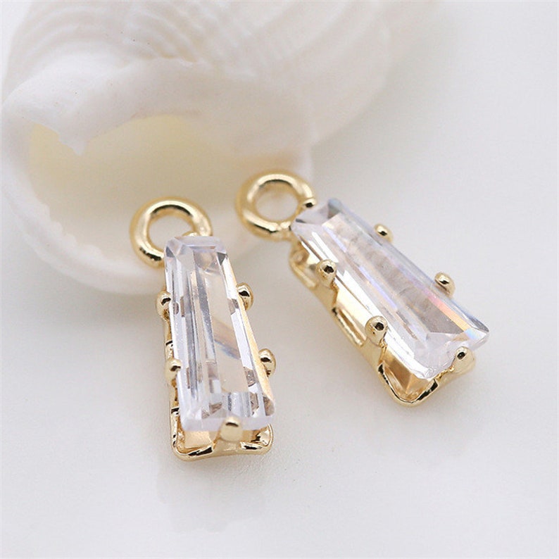 May include: Two gold-tone earring charms with clear rectangular crystal stones.
