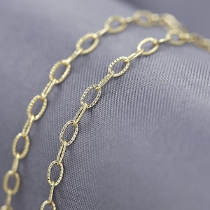 Könnte beinhalten: Eine goldene Kettenkette mit einem strukturierten ovalen Gliederdesign.