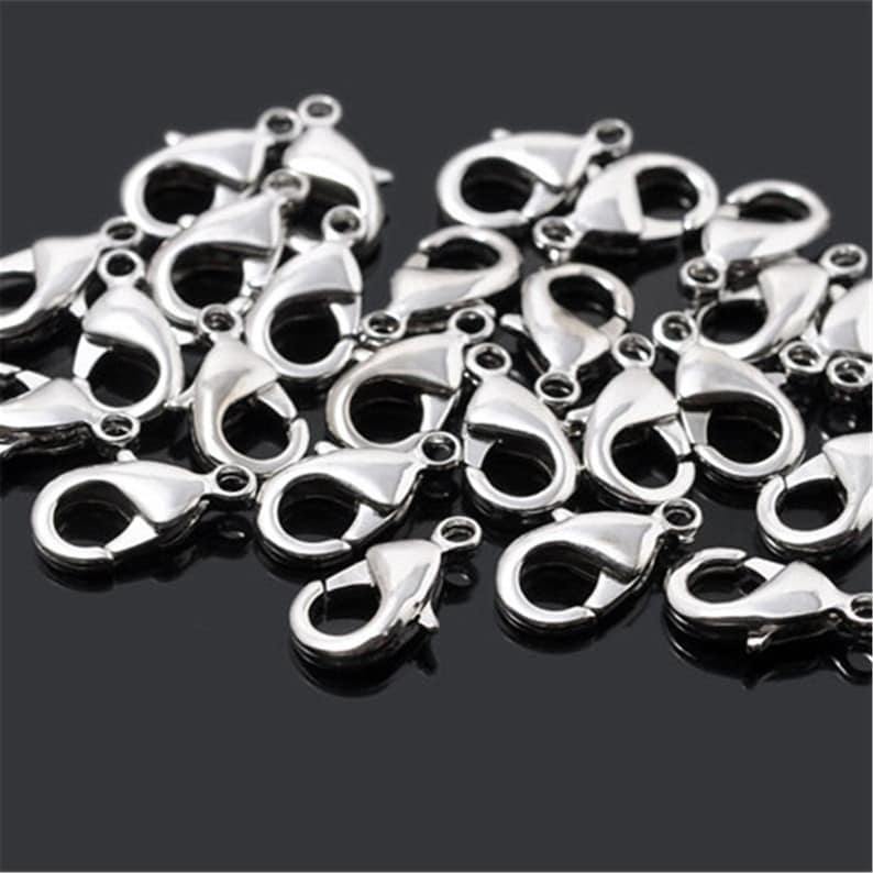 May include: A pile of silver-toned lobster clasps, a type of fastener used for jewelry making.