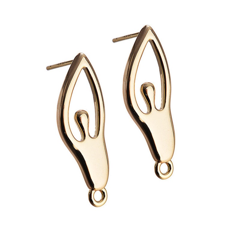 May include: A pair of gold-toned earrings featuring a stylized human figure design. The earrings have a post and butterfly closure.