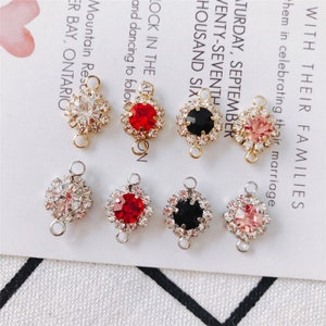 May include: Six different charm pendants with a gold setting and a clear, red, black, or pink rhinestone centre. Each pendant has two loops for attaching to a chain or bracelet.