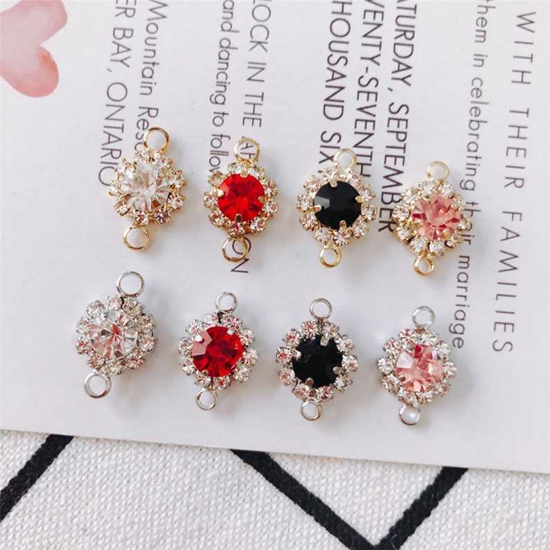 May include: Six different charm pendants with a gold setting and a clear, red, black, or pink rhinestone centre. Each pendant has two loops for attaching to a chain or bracelet.