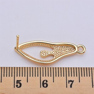 May include: Gold-tone metal earring finding with a decorative, openwork design. The finding measures approximately 1.75 inches in length.