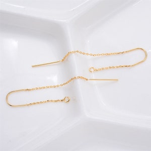 May include: A pair of gold chain earrings with a small bar hanging from each chain.