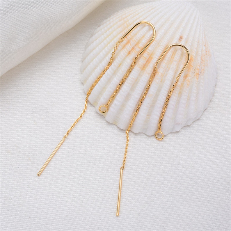 May include: A pair of gold-toned dangle earrings with a delicate chain and a straight bar pendant.