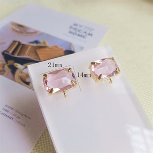 May include: Two pink glass rectangular earrings with gold metal settings. The earrings measure 21 mm by 14 mm.