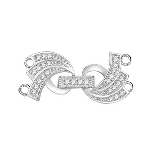 May include: Silver tone clasp with a decorative design featuring two curved pieces with clear stones. The clasp has two loops on each side for attaching to a necklace or bracelet.