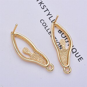 May include: Two gold-tone earring findings with a cutout design of a person. The findings have a loop at the bottom for attaching a dangle.