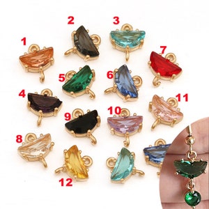 Puede incluir: Doce abalorios de metal dorado con piedras de cristal de diferentes colores en forma de semicírculo. Cada abalorio tiene un bucle para sujetarlo a un collar, pulsera u otra joya.