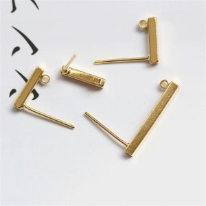 May include: Three gold-toned earring posts with a rectangular bar at the top. The bars are smooth and have a slightly rounded edge. The posts are straight and have a small loop at the top.