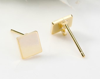 May include: A pair of gold square stud earrings with a white center.