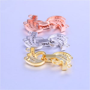May include: Three different colored metal clasps for necklaces or bracelets. The clasps are in the shape of a crescent moon with a decorative design and have a small, rectangular latch. The clasps are gold, silver, and rose gold.