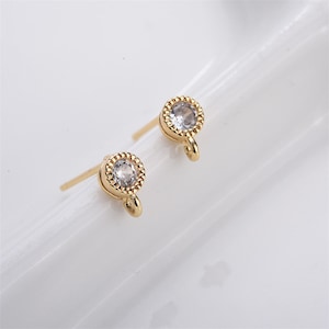 May include: A pair of gold-tone earring findings with a small clear rhinestone in the center of each. Each finding has a small loop at the bottom.