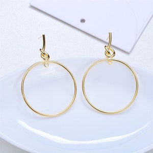 May include: A pair of gold hoop earrings with a knotted detail at the top of each hoop.